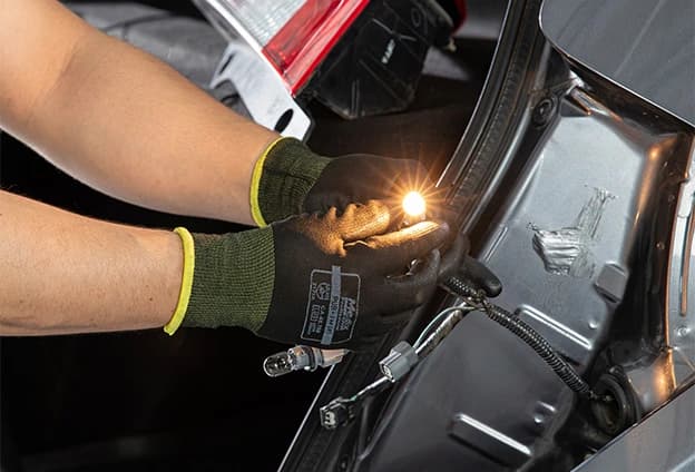 imagem de um farol de carro aceso durante a noite. O farol possui cor vermelha